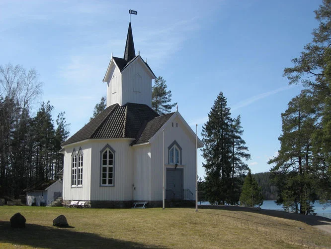 Kilebygda kirke med vannet i bakgrunnen. Foto.