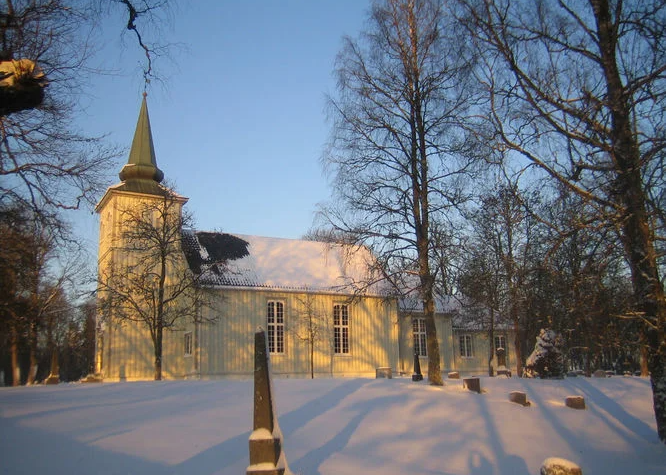 Solum kirke i vinterlandskap. Gravminne i forkant. Foto.